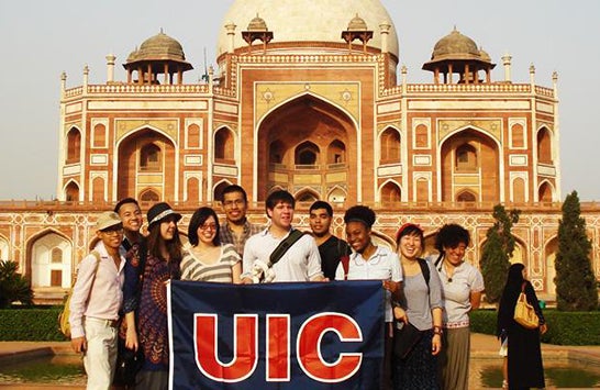 Students holding a UIC flag in front of a mosque in an unknown foreign country