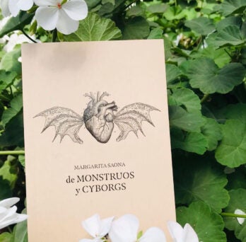 Photo of book in flower bush, heart with wings. De monstrous y cyborgs on cover
                  